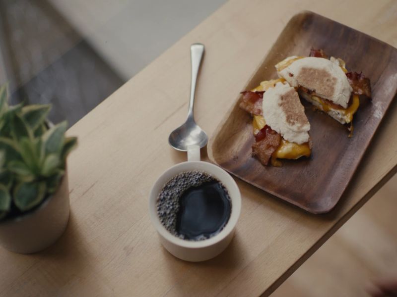 Šoljica crne kafe i tacna pored sa doručkom, tost sa jajima
