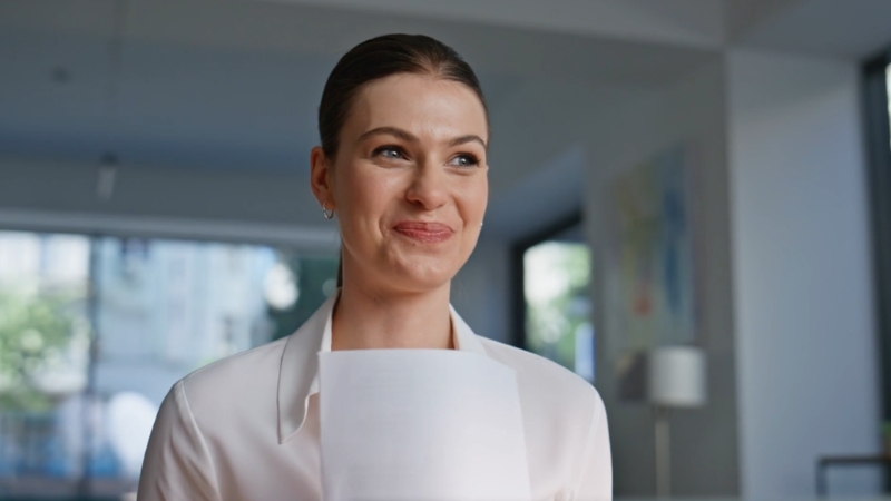 Žena sa osmehom drži dokument u rukama, zadovoljna nakon uspešnog procesa otvaranja firme u Srbiji