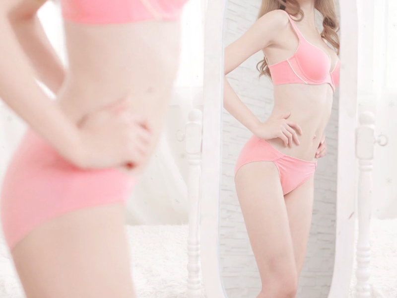 devojka u roze donjem vešu se gleda u ogledalo i pozira