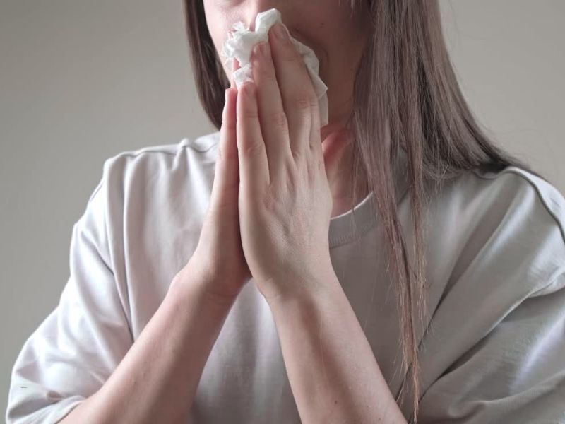 devojka koja pati od alergije duva nos u maramicu