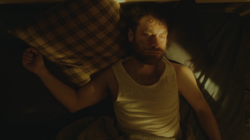 Muškarac leži u krevetu sa napetim izrazom lica, kao da se često budi tokom noći