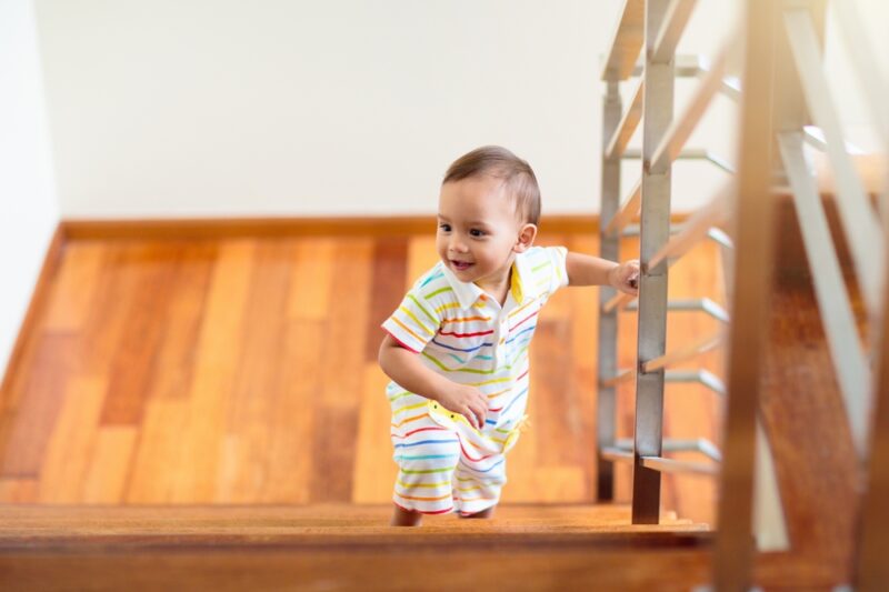 Malo dete se penje uz stepenice u kući držeći se za ogradu