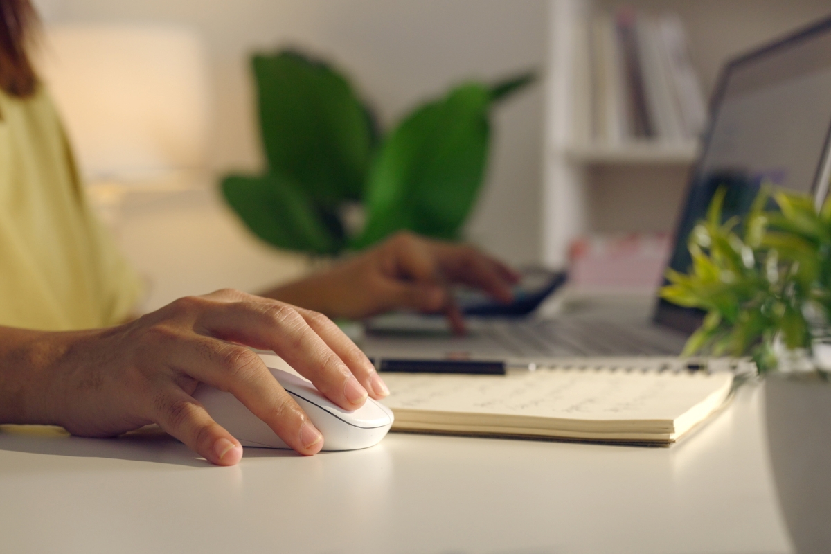 osoba koristi laptop uz pomoć miša