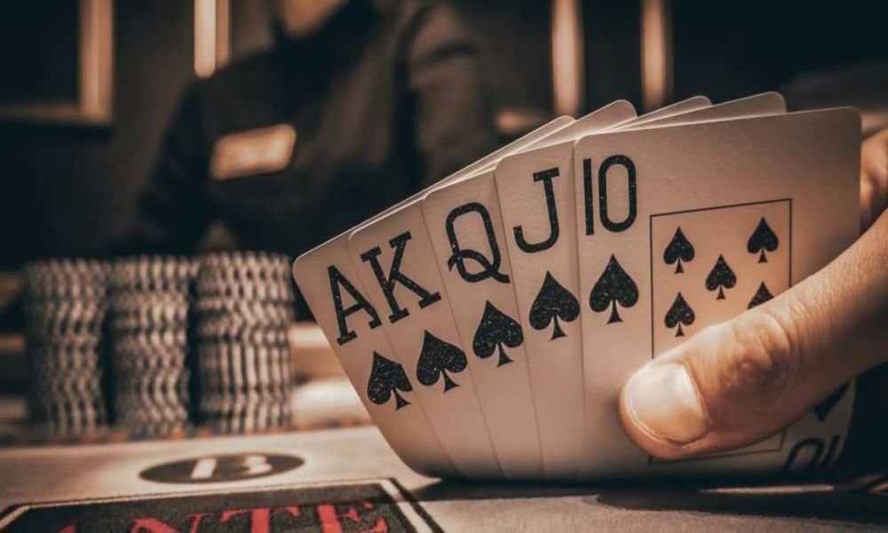 Igrač drži poker karte u ruci tokom partije Caribbean stud pokera u kazino okruženju