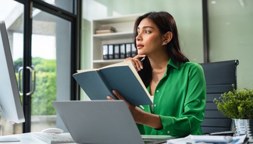Žena u kancelariji razmišlja i zapisuje ideje za razvoj suštine brenda