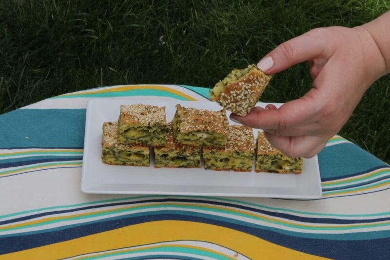 prikaz servirane pite sa sremušem na belom tanjiru i osobe koja drži parče pite u ruci