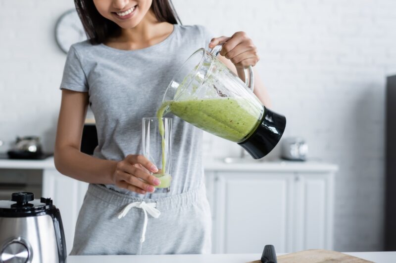 devojka sipa zeleni smuti u čašu i smeje se