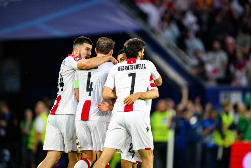 Fudbaleri Gruzije u belim dresovima slave pogodak tokom utakmice pred navijačima na stadionu.
