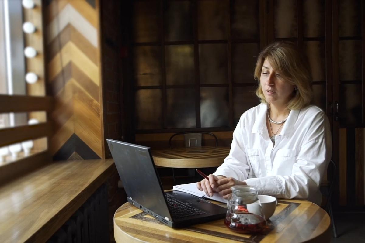 devojka sedi u lokalu i koristi laptop i notes