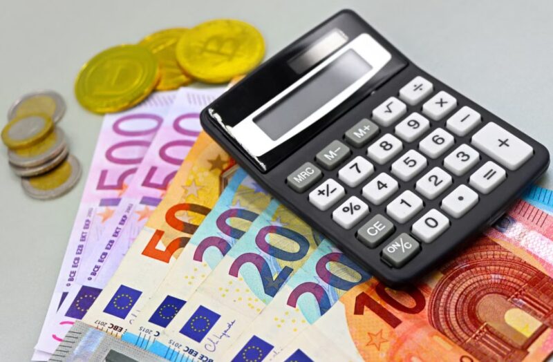 Crni kalkulator na novčanicama od 50, 100, 200 i 500 evra, uz nekoliko metalnih novčića